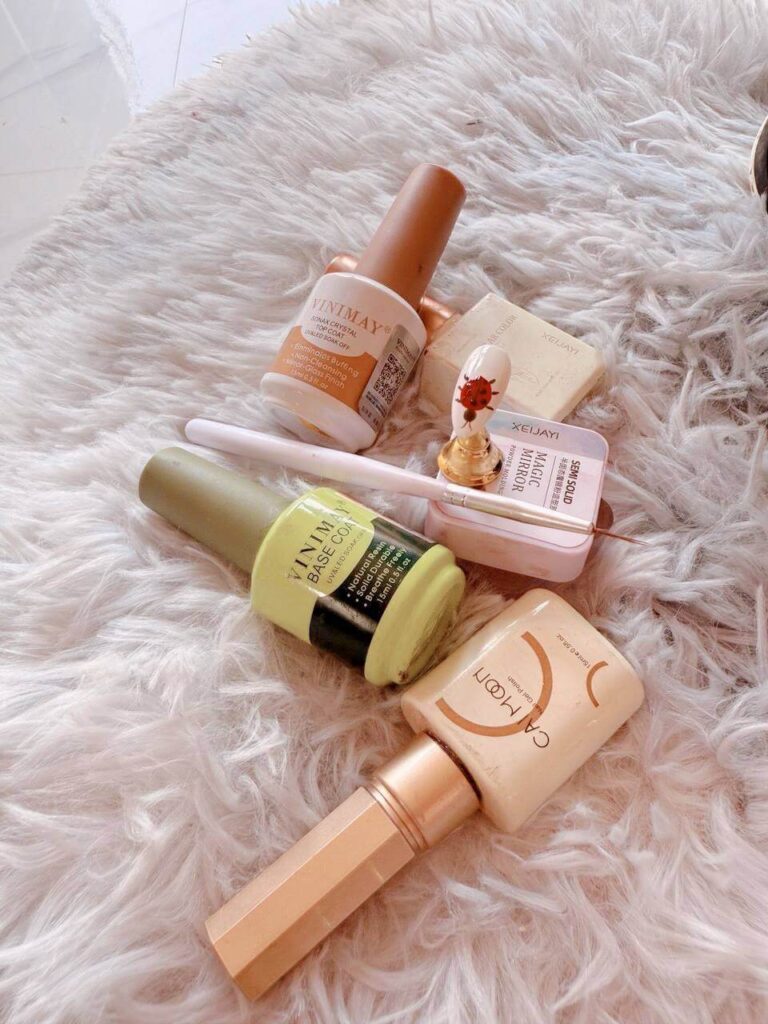 Flat lay of gel nail polish supplies including VINIMAY base coat, top coat, and a detailing brush.