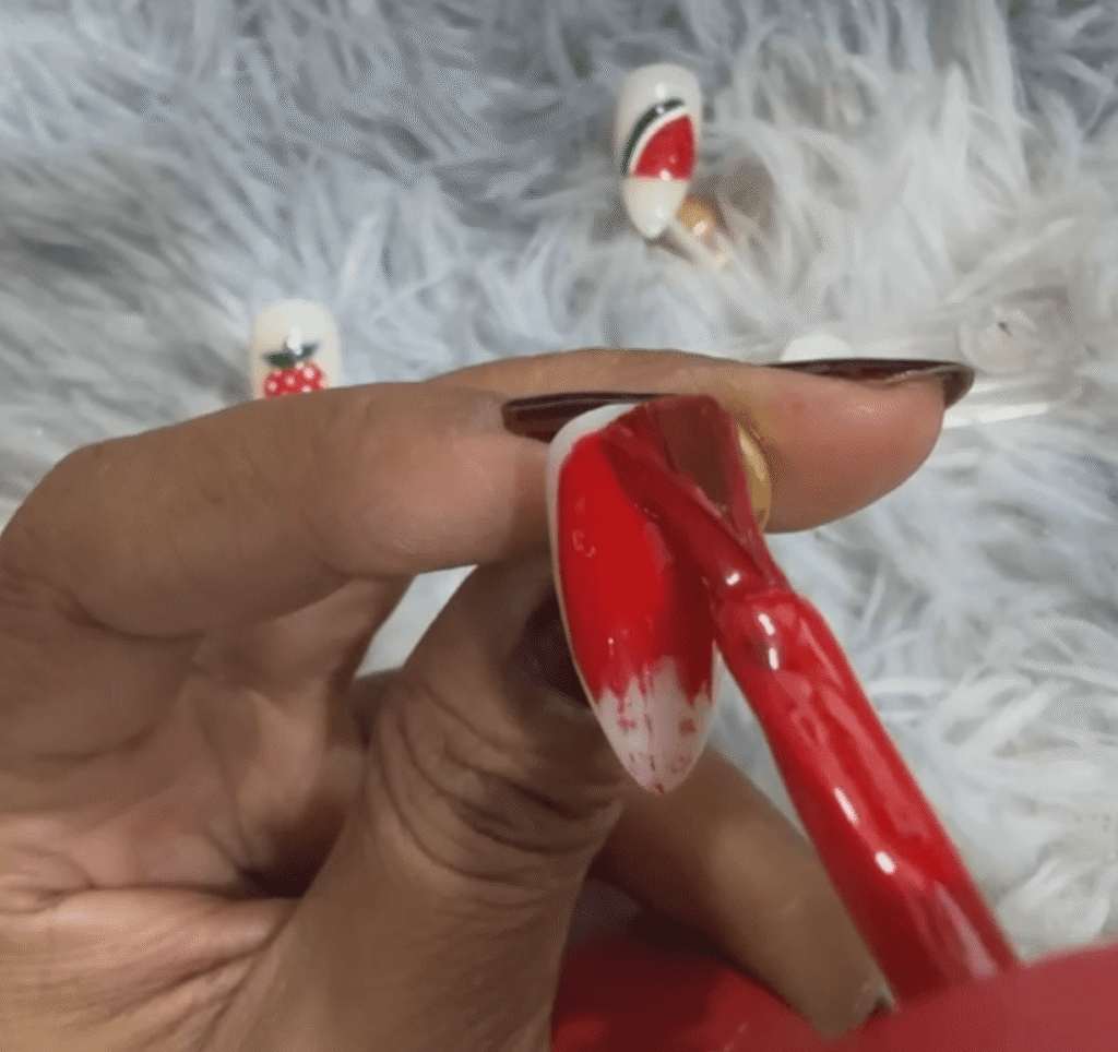 Applying red polish heavily at the tip of the nail before fading it downward to create a gradient effect.